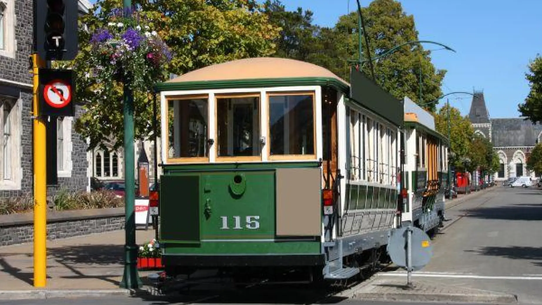 A green tram travels down a road in Christchurch, New Zealand