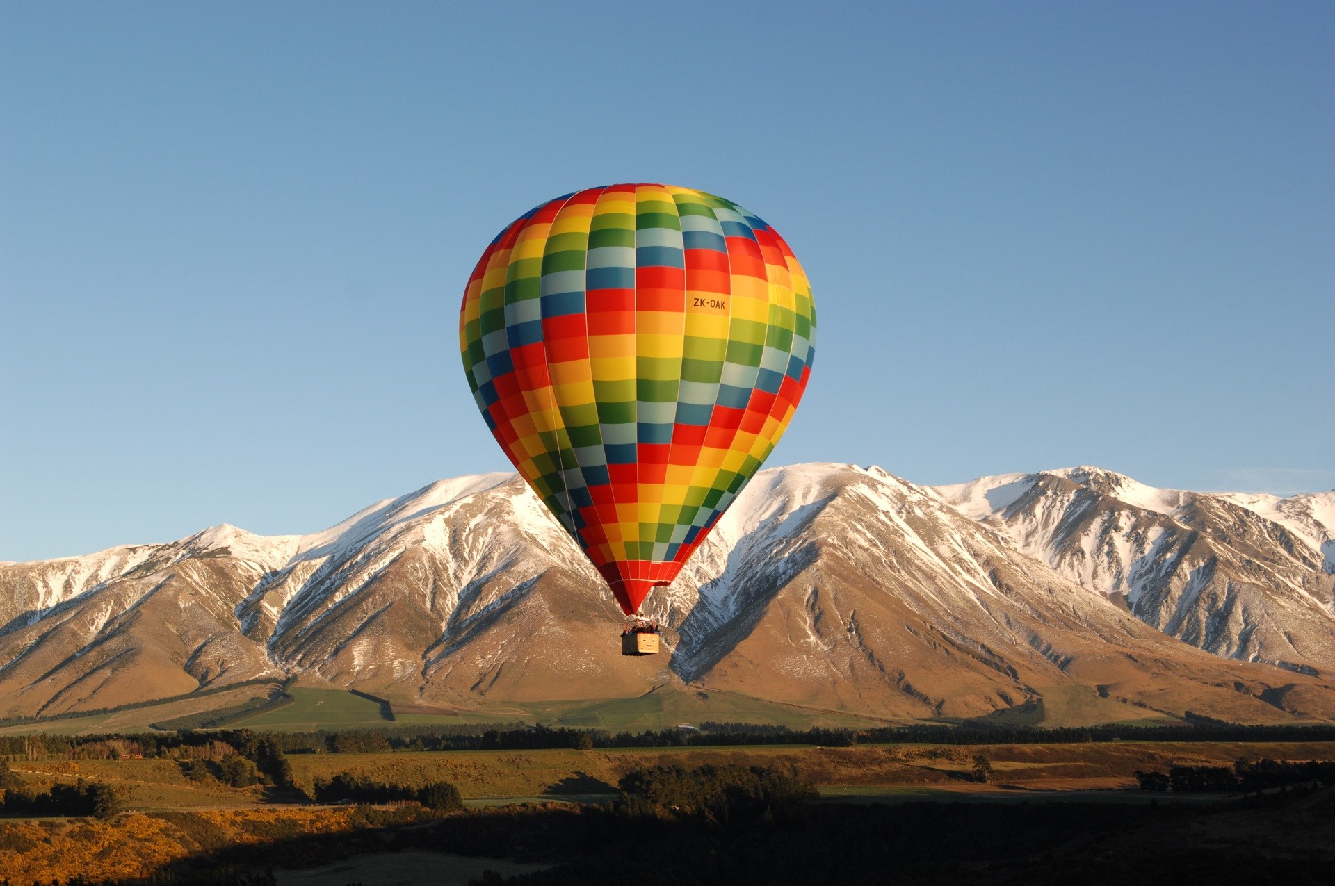 Bunter Heißluftballon fliegt vor Bergkulisse