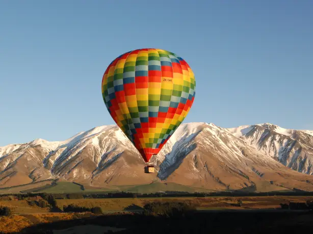 Bunter Heißluftballon fliegt vor Bergkulisse