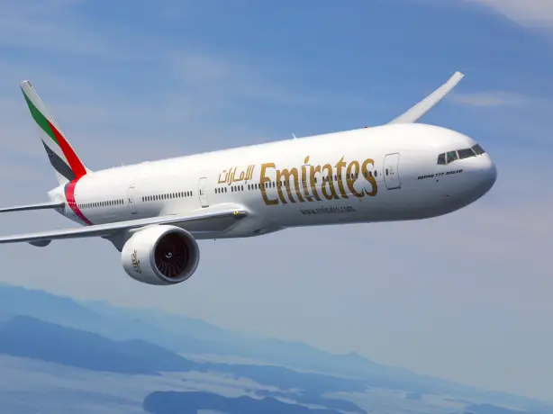 Fliegendes Emirates Flugzeug oberhalb von Bergen und Gewässer