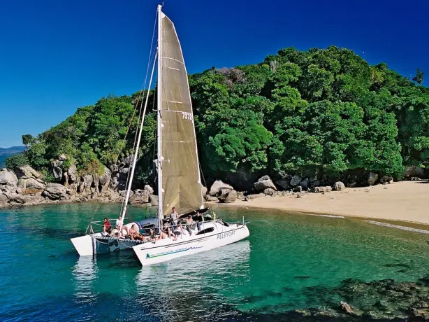 Menschen auf einem Segelboot in einer Bucht in Abel Tasman, Neuseeland