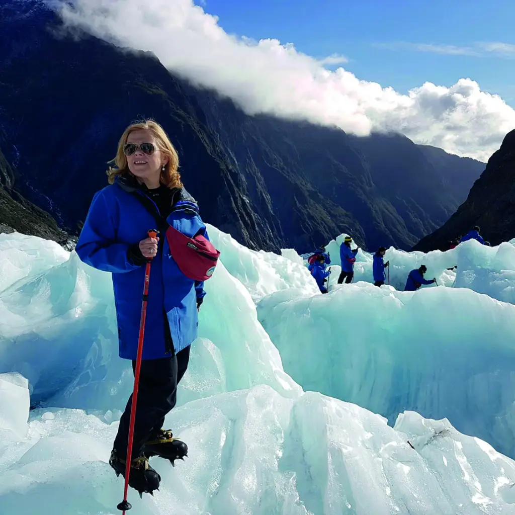 Frau beim Wandern auf dem Fox-Gletscher mit anderen Wanderern im Hintergrund