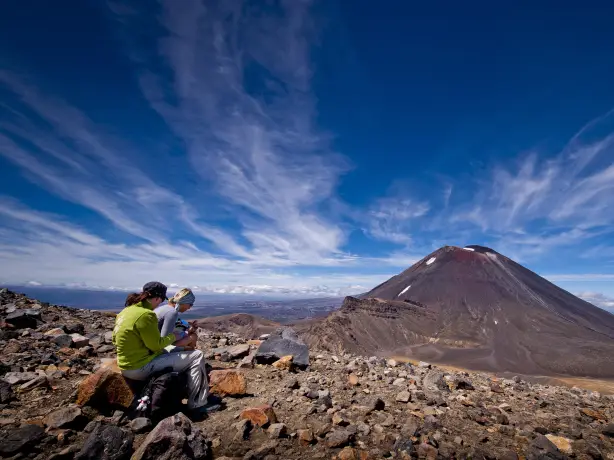 Zwei Frauen sitzen auf einem Felsen beim Tongariro Alpine Crossing in Neuseeland