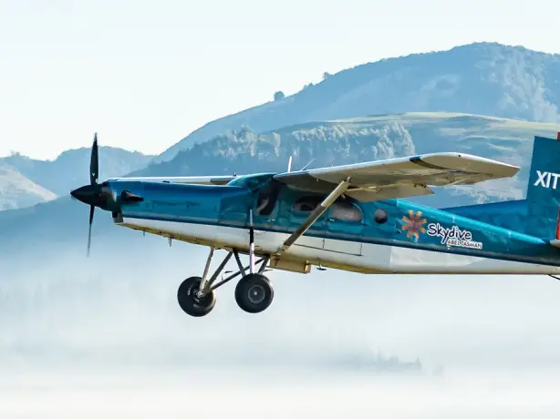 Kleinflugzeug fliegt vor nebeliger Hügellandschaft