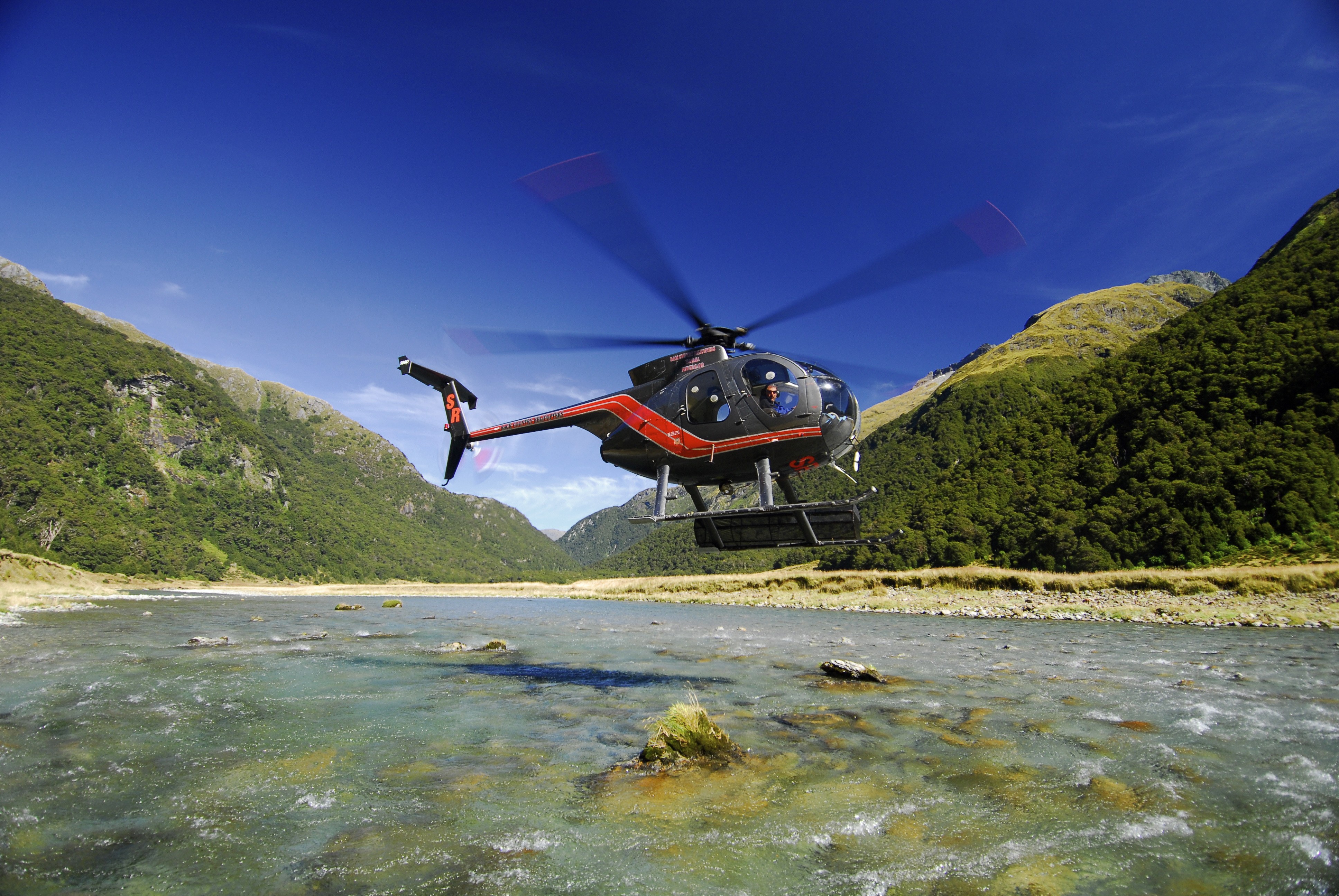 Helikopter schwebt über Gewässer vom Mount Aspiring National Park