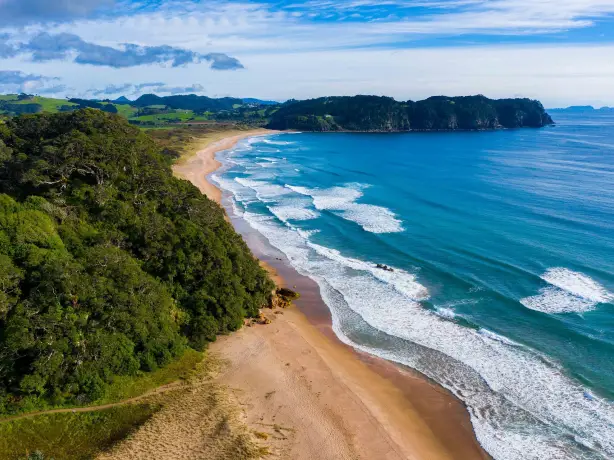 Luftaufnahme von Hot Water Beach mit Meer und grüner hügeliger Landschaft
