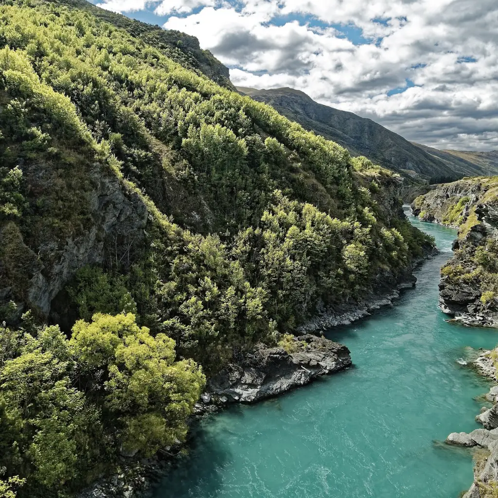 Blick auf den Kawarau-Fluss mit hellblauem Wasser, das durch eine tiefe, grün bewachsene Schlucht fließt