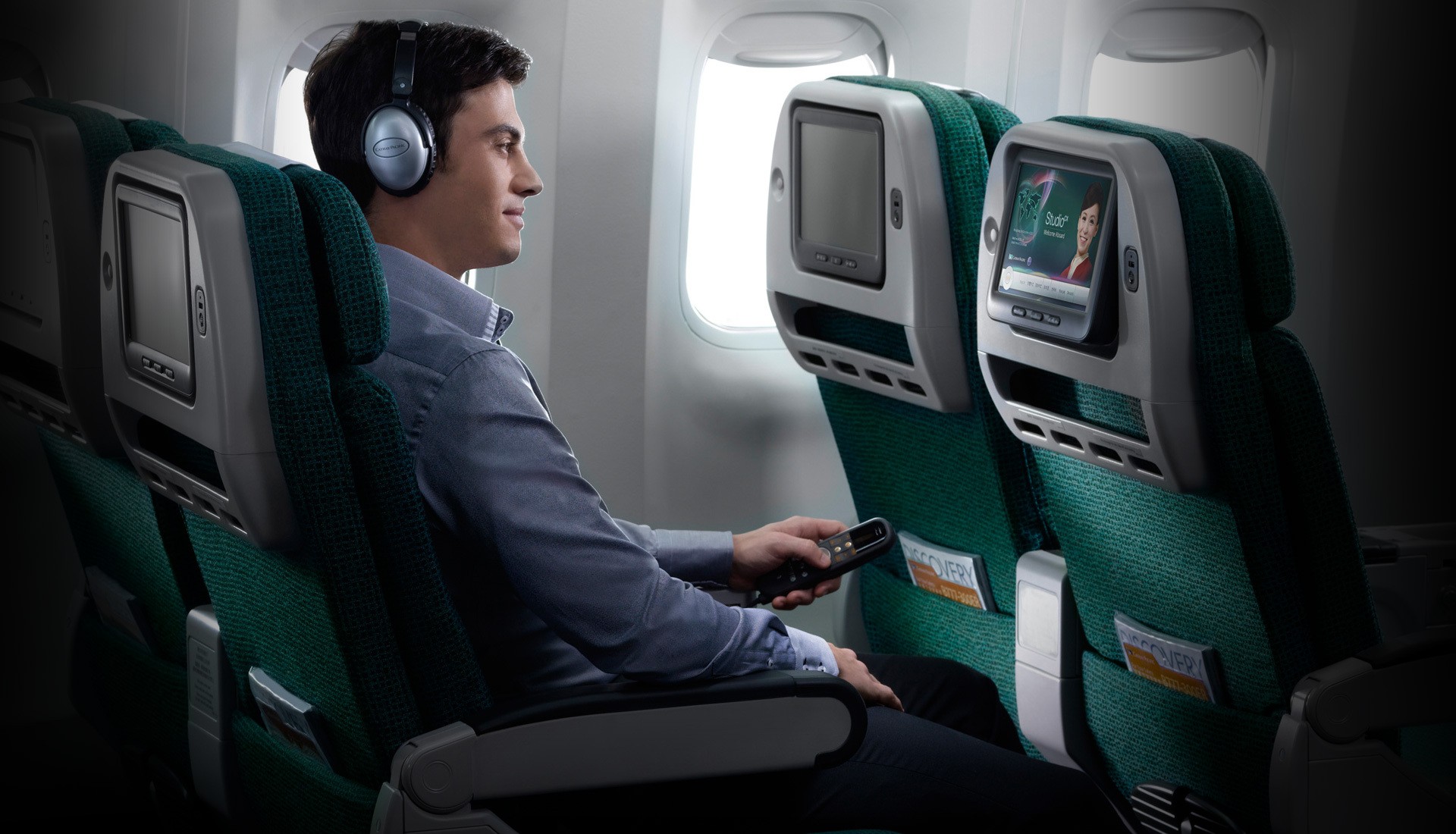 Mann sitzt im Cathay Pacific Flugzeug und blickt in einen Screen