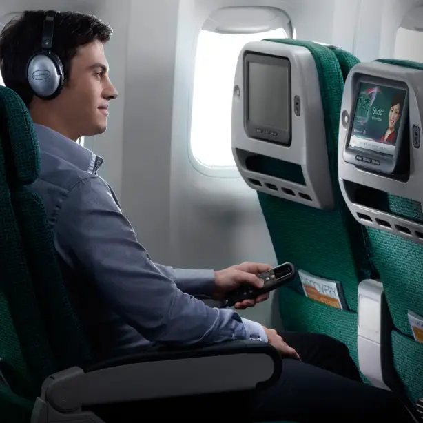 Mann sitzt im Cathay Pacific Flugzeug und blickt in einen Screen