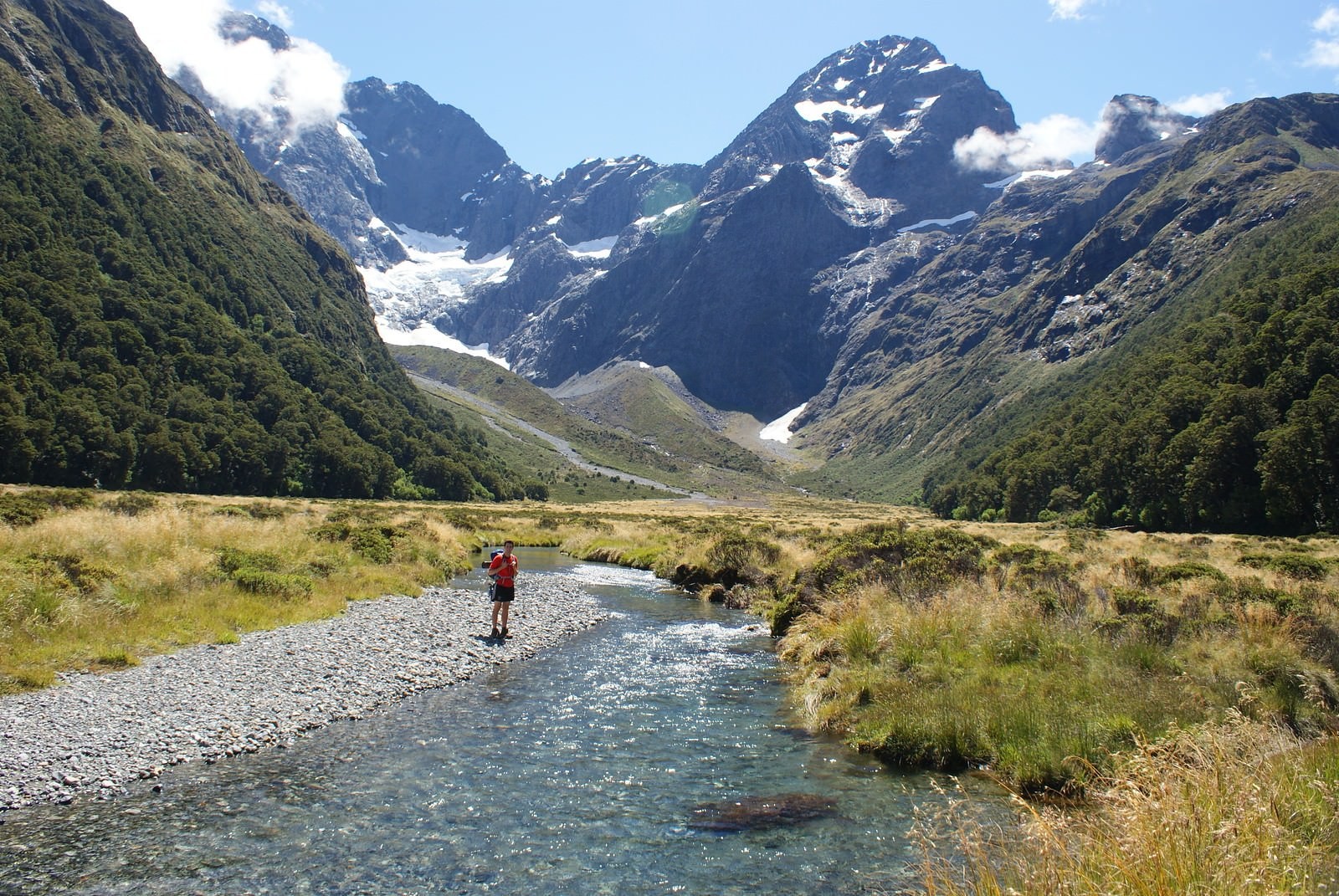 A person stands by a river during a hike in Fiordland National Park, New Zealand