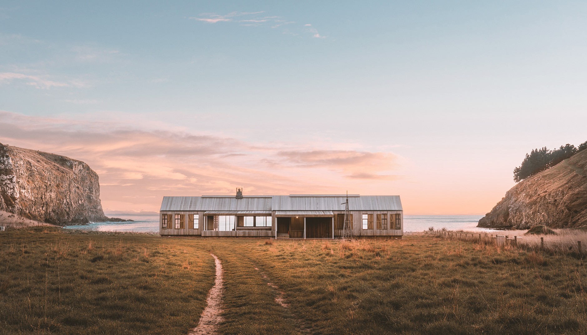 Stilvolles, großes Holzhaus vor einer Bucht mit Blick aufs Meer