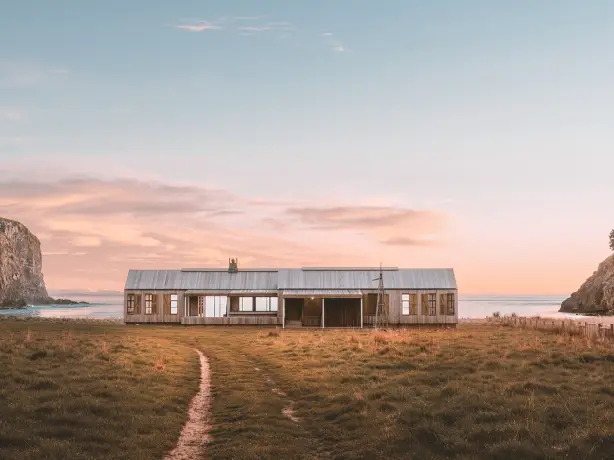 Stilvolles, großes Holzhaus vor einer Bucht mit Blick aufs Meer
