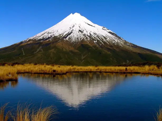 Ein schneebedeckter Berg im Hintergrund, der sich im See spiegelt, Mount Taranaki im Egmont National Park - Neuseeland