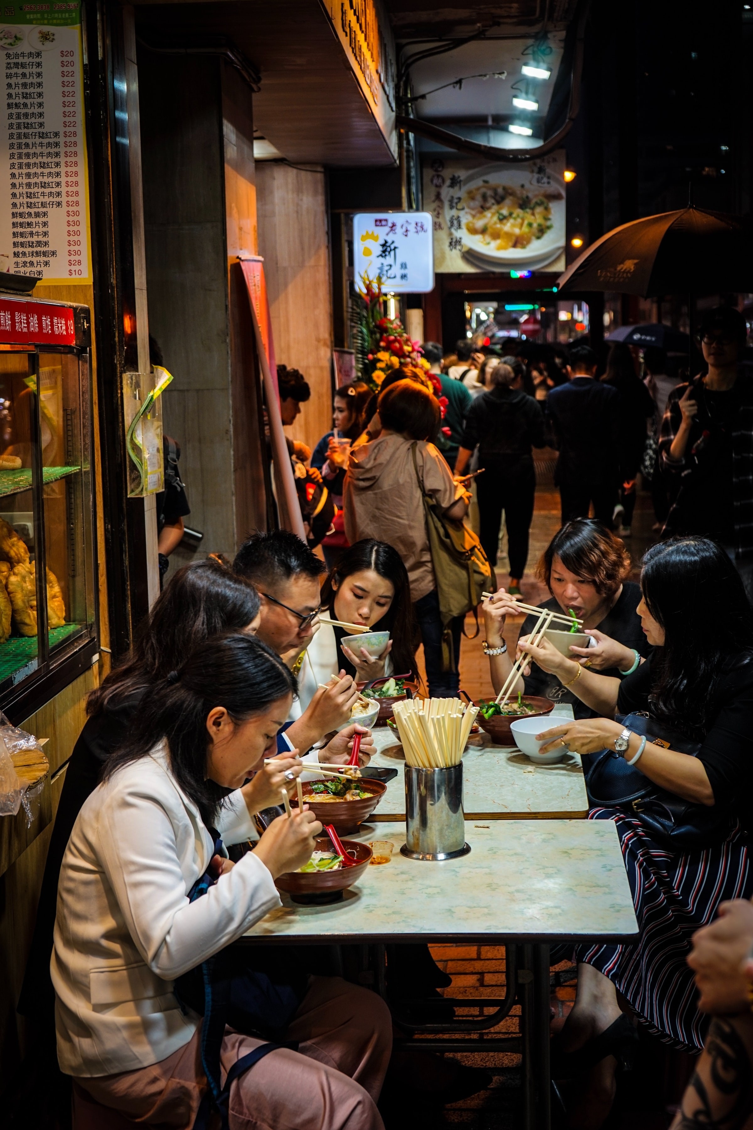 A family sitting at a table eating food outside a restaurant in Hong-Kong