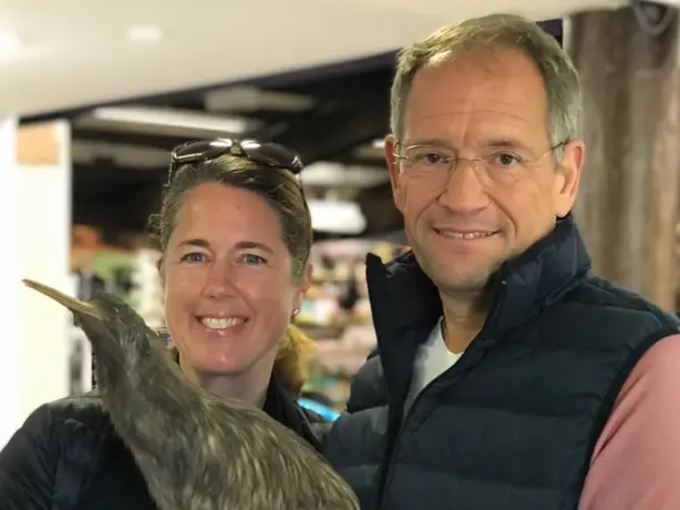A British couple pose for the camera holding a stuffed kiwi