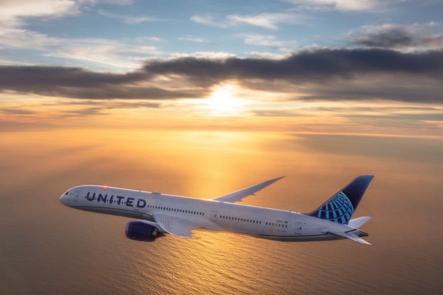 Flugzeug von United airlines fliegt bei Sonnenuntergang über Wasser