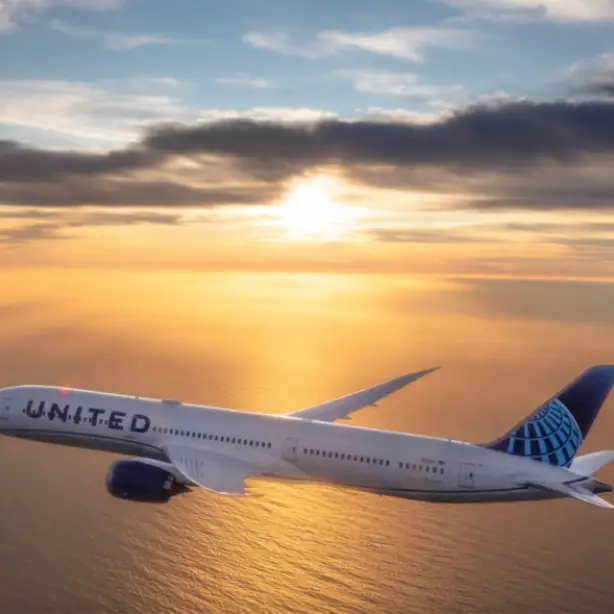 Flugzeug von United airlines fliegt bei Sonnenuntergang über Wasser