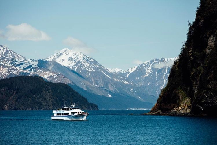 image of the Kenai Fjords boat tour with snow covered mountains in the background