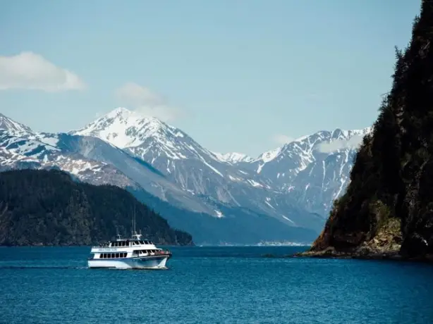 image of the Kenai Fjords boat tour with snow covered mountains in the background