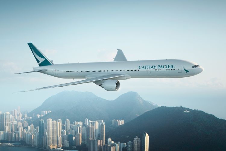 Flugzeug von Cathay Pacific fliegt über Stadt mit Hochhäusern