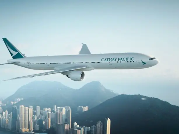 Flugzeug von Cathay Pacific fliegt über Stadt mit Hochhäusern