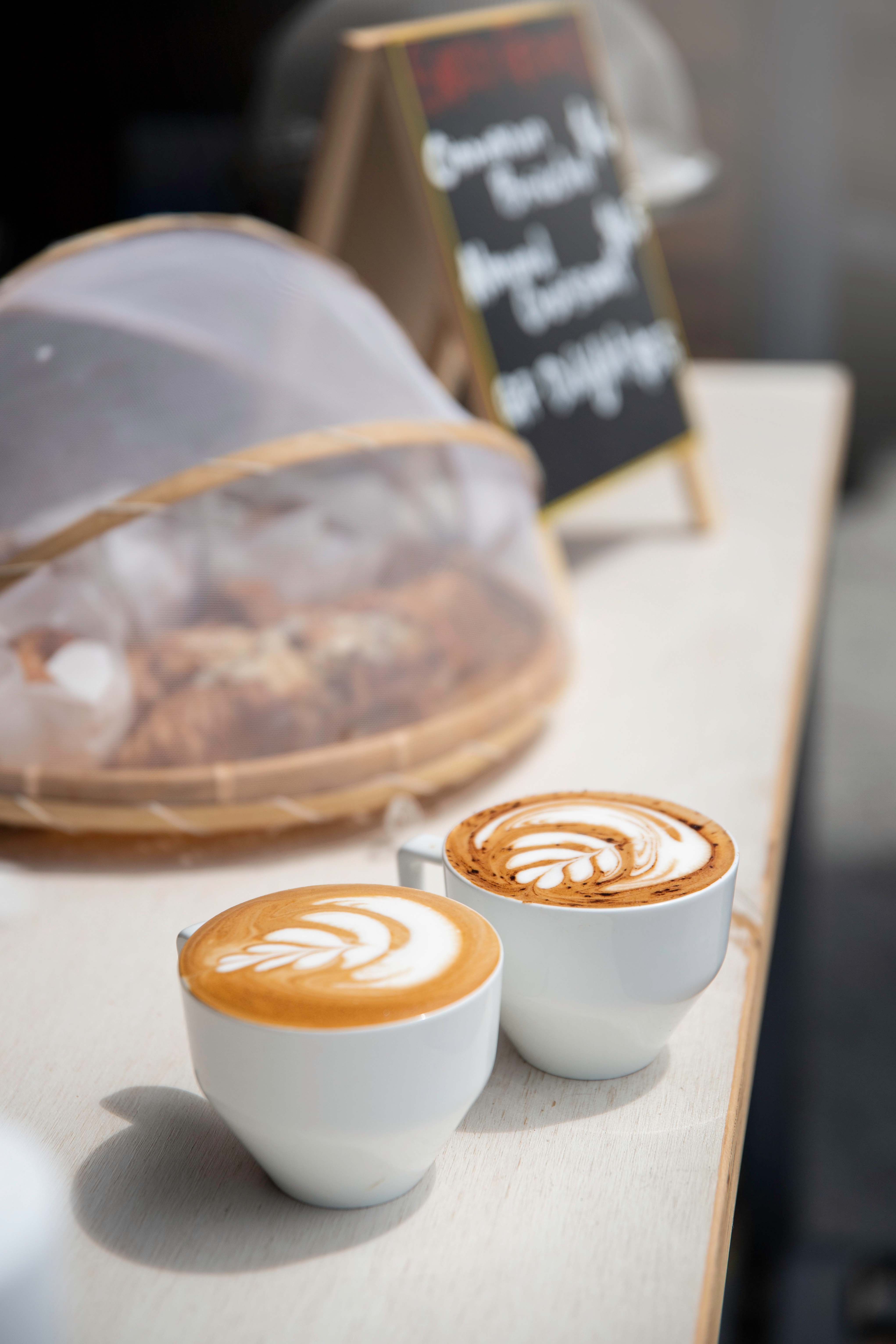 two coffees sitting on a counter in a cafe