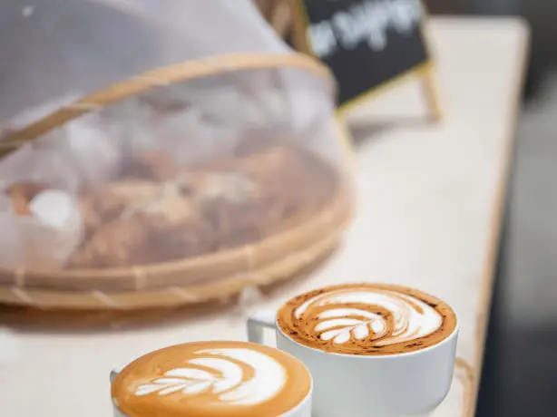 two coffees sitting on a counter in a cafe