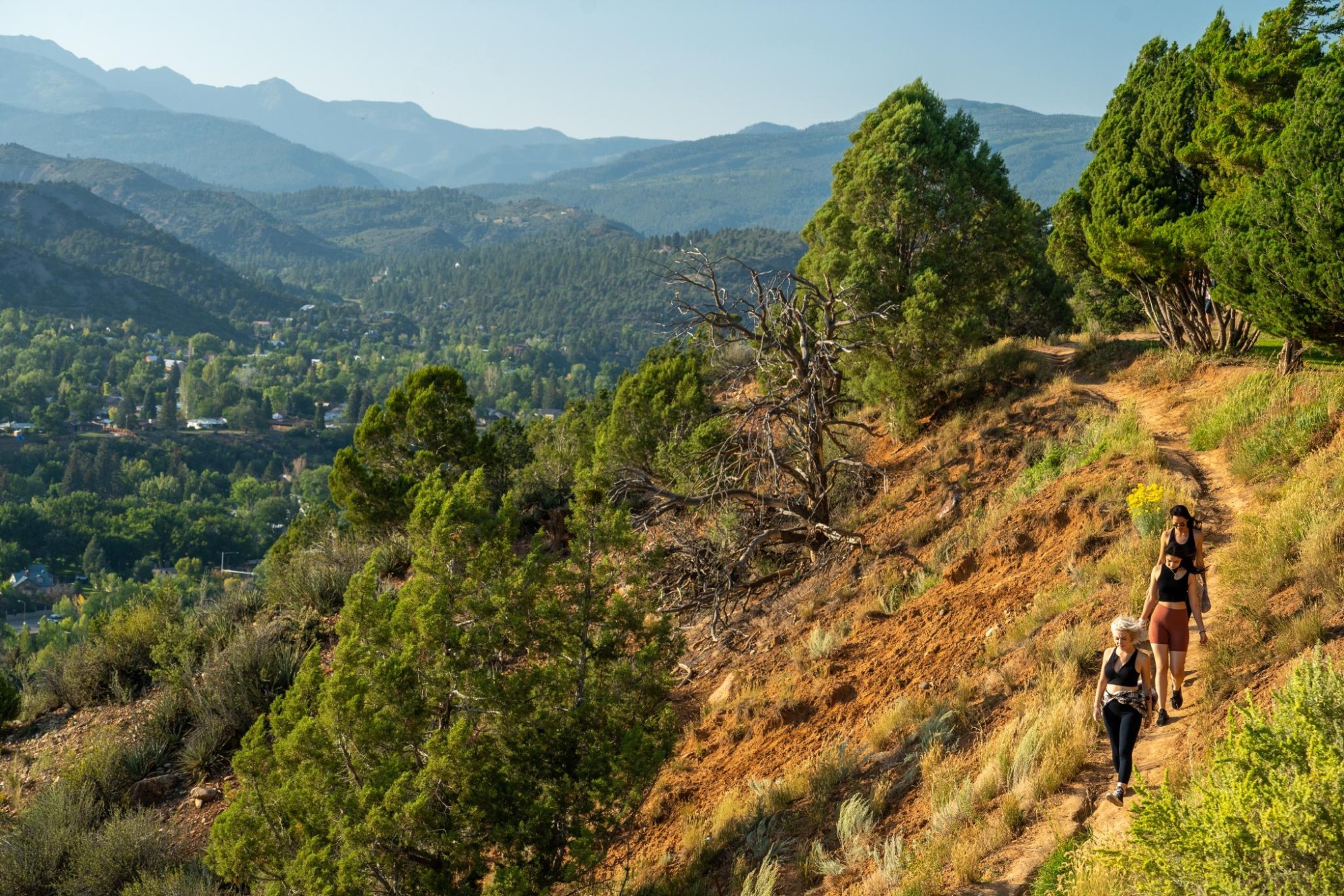 Drei Frauen wandern entlang des Rim Trail in Fort Lewis bei Sonnenuntergang