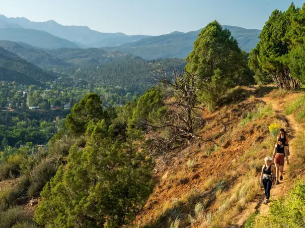 Drei Frauen wandern entlang des Rim Trail in Fort Lewis bei Sonnenuntergang