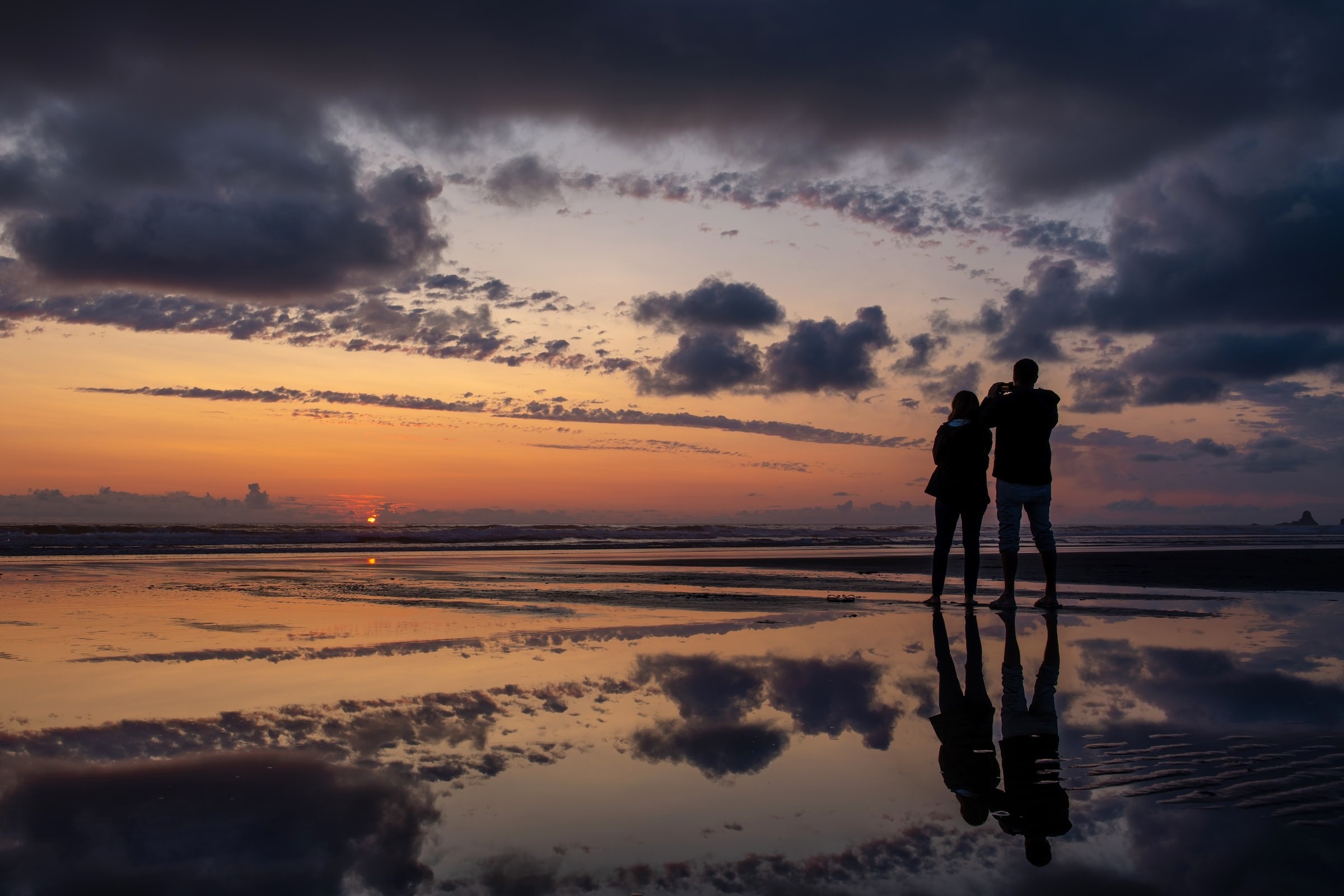 Ein Paar, das den Sonnenuntergang am Cannon Beach in Oregon beobachtet