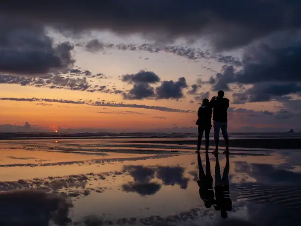 Ein Paar, das den Sonnenuntergang am Cannon Beach in Oregon beobachtet