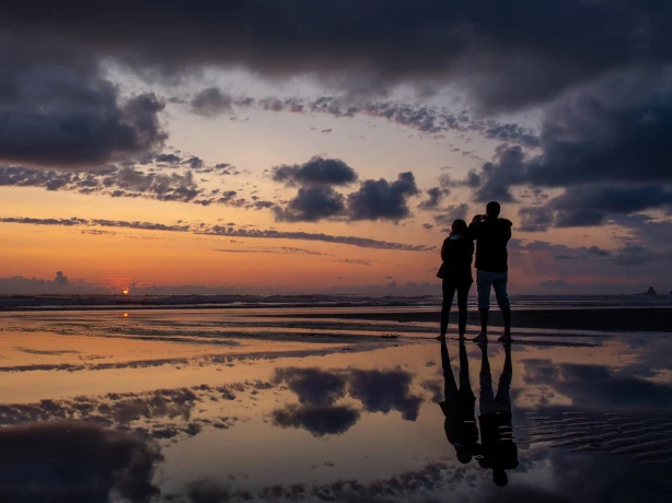 Ein Paar, das den Sonnenuntergang am Cannon Beach in Oregon beobachtet