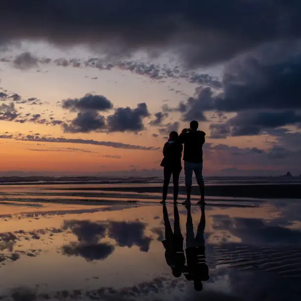 Ein Paar, das den Sonnenuntergang am Cannon Beach in Oregon beobachtet