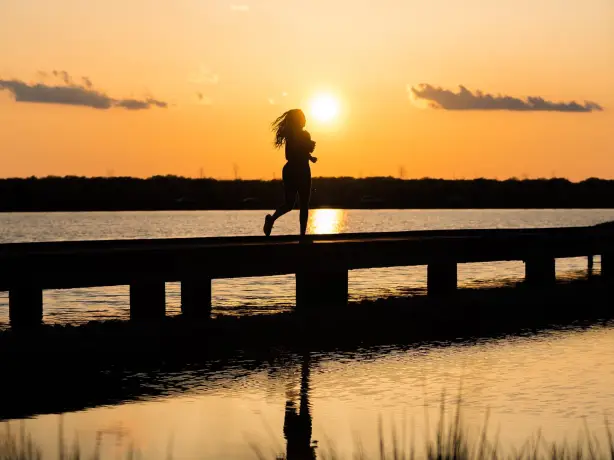 Frau läuft bei Sonnenuntergang über einen Steg am Wasser in Memphis, USA