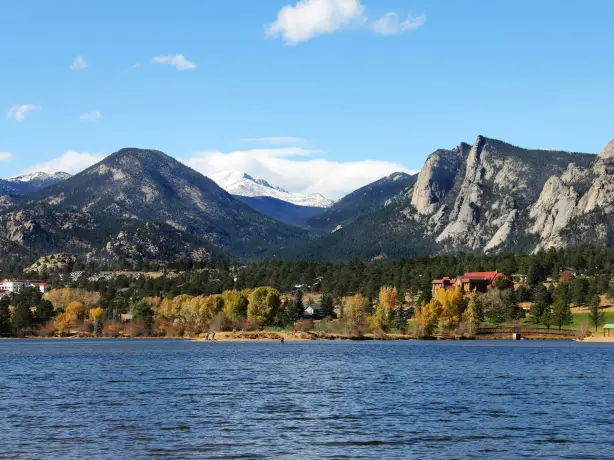 Ruhiger See mit Bergpanorama im Hintergrund und herbstlicher Wald in Estes Park, Colorado
