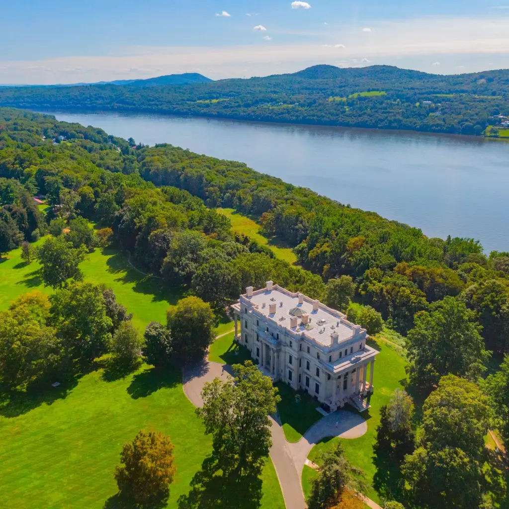 Großes Herrenhaus umgeben von Parklandschaften und Bäumen mit Fluss im Hintergrund