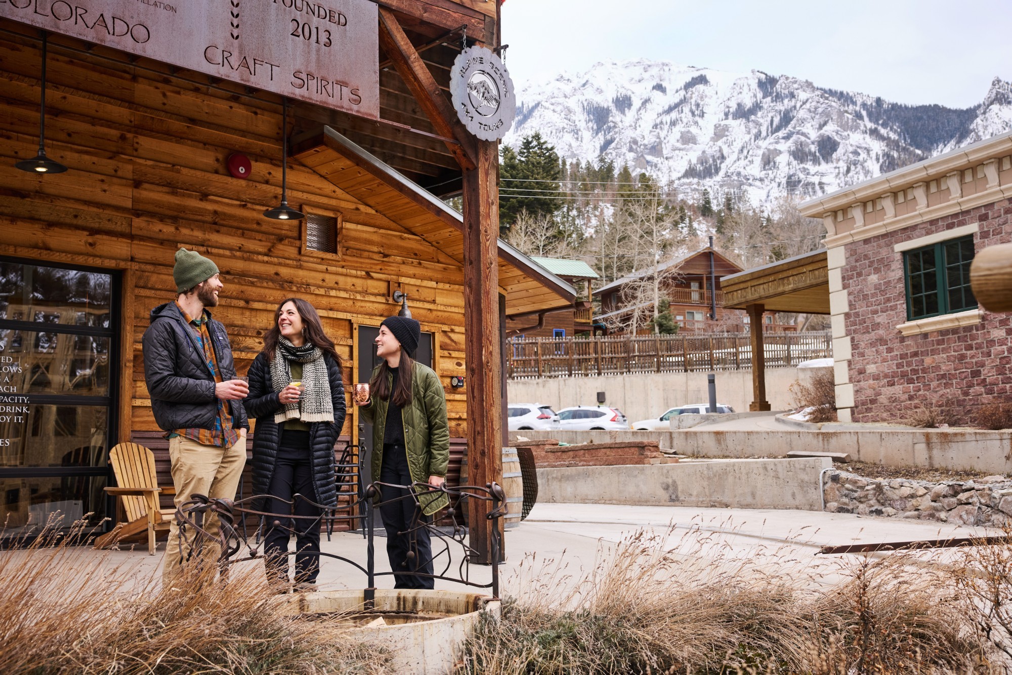 Drei Freunde genießen gemeinsam einen Drink vor einer Craft-Destillerie in Ouray, Colorado