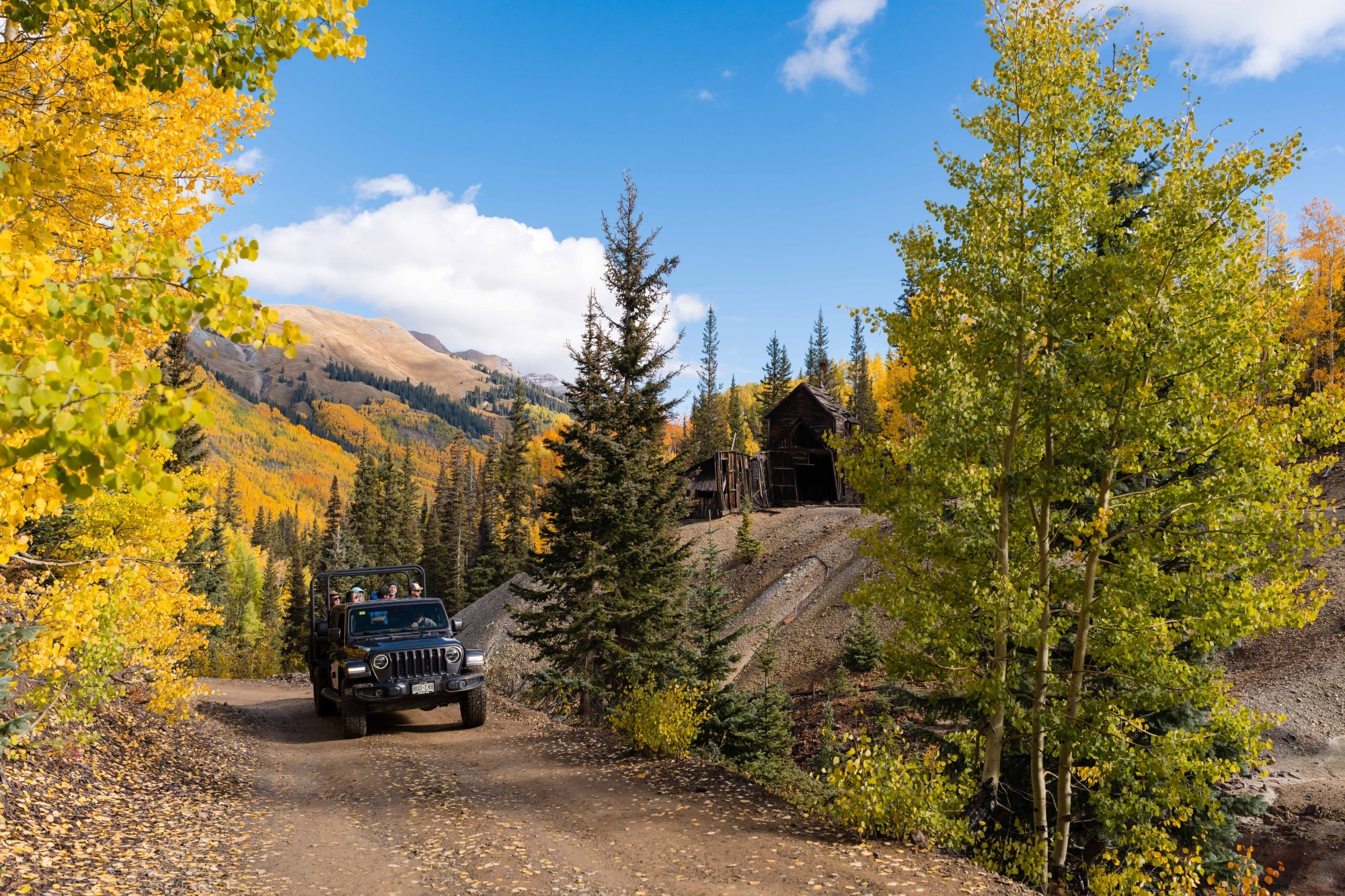 Jeep mit Urlaubern fährt durch die herbstliche Landschaft von Ouray, Colorado