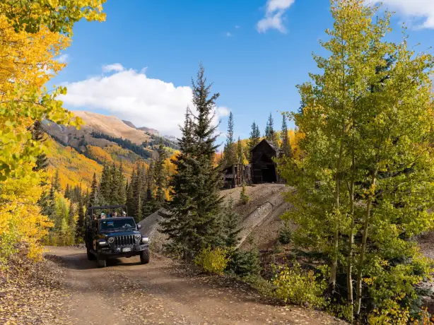 Jeep mit Urlaubern fährt durch die herbstliche Landschaft von Ouray, Colorado