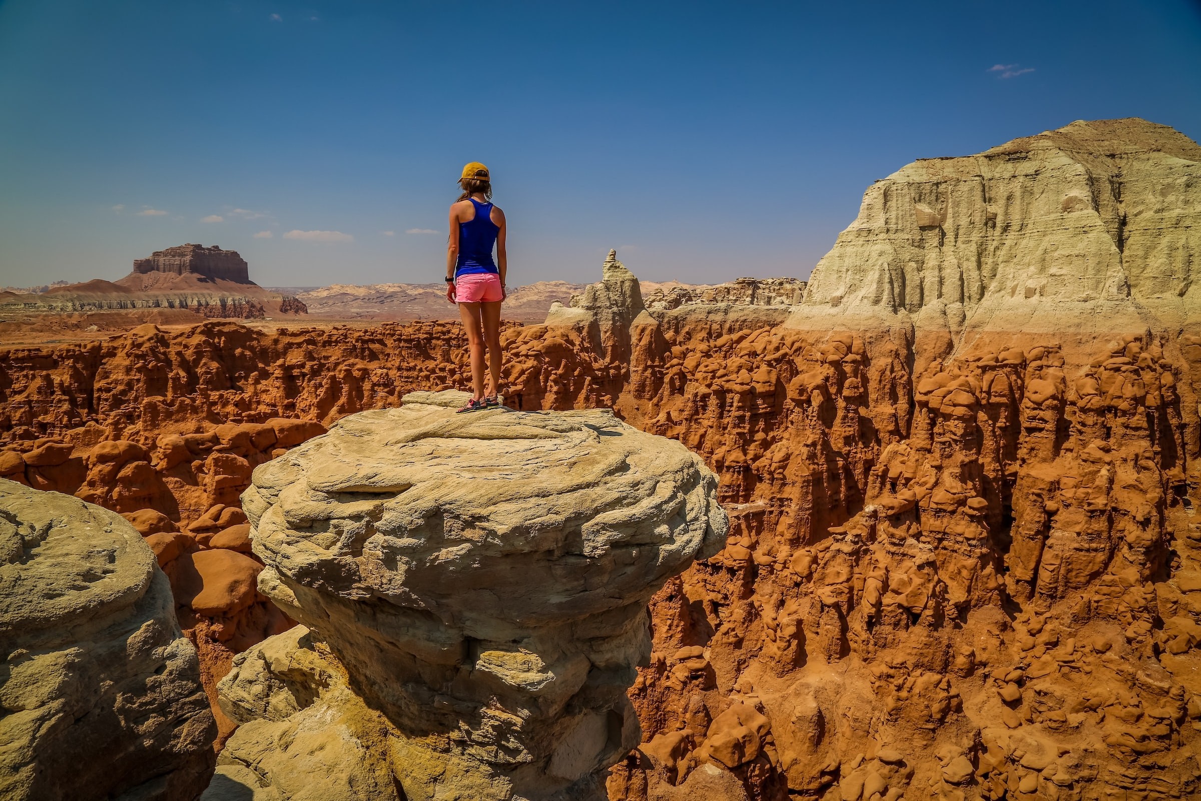 Ein Wanderer steht auf einem Felsvorsprung und überblickt die geformten roten Felsformationen und die Wüstenlandschaft des amerikanischen Südwestens.