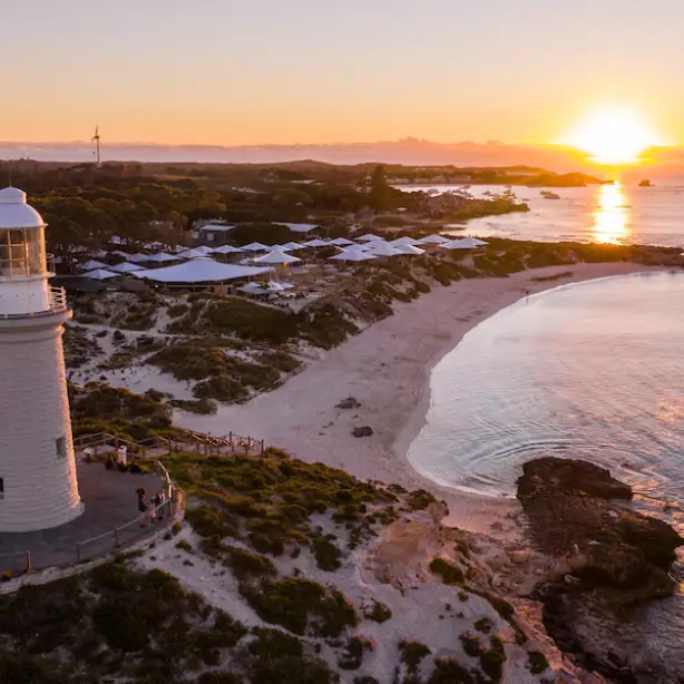 Een vuurtoren aan de kust met een zonsondergang op de achtergrond