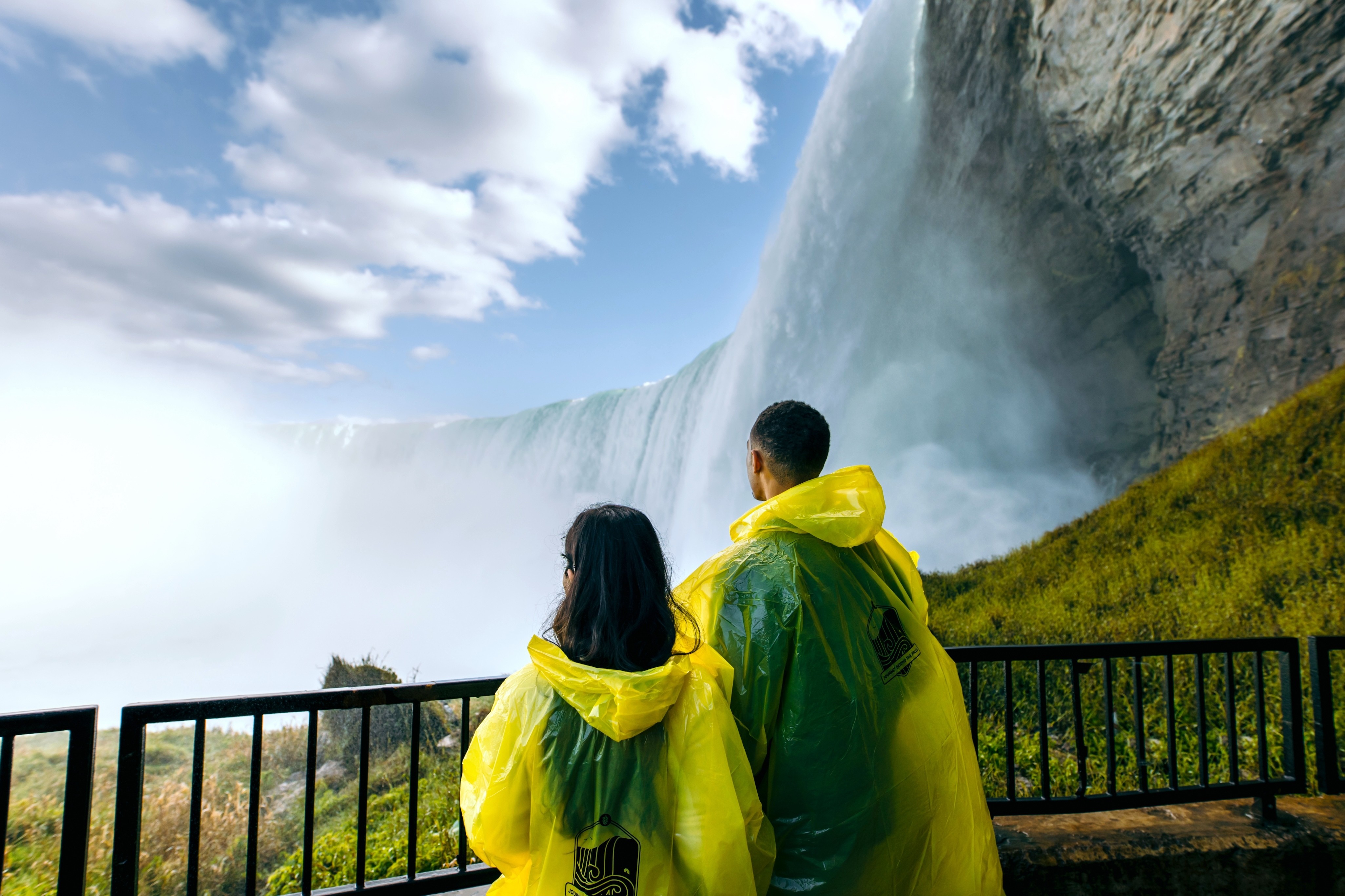 Ein Paar in wasserdichten Ponchos blickt auf die tosenden Niagarafälle in Kanada.