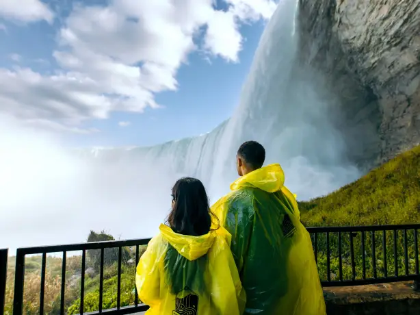 Ein Paar in wasserdichten Ponchos blickt auf die tosenden Niagarafälle in Kanada.
